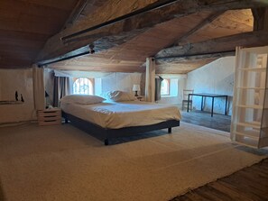 Un dormitorio con cama, piso de madera, ventana y puerta.
