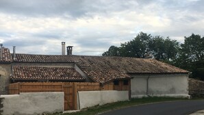 Ein traditionelles Gebäude mit Ziegeldach und Holztür, neben einer gepflasterten Straße.