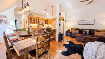 A modern kitchen with wooden cabinets, a dining table set with placemats, and a black dog on the floor.