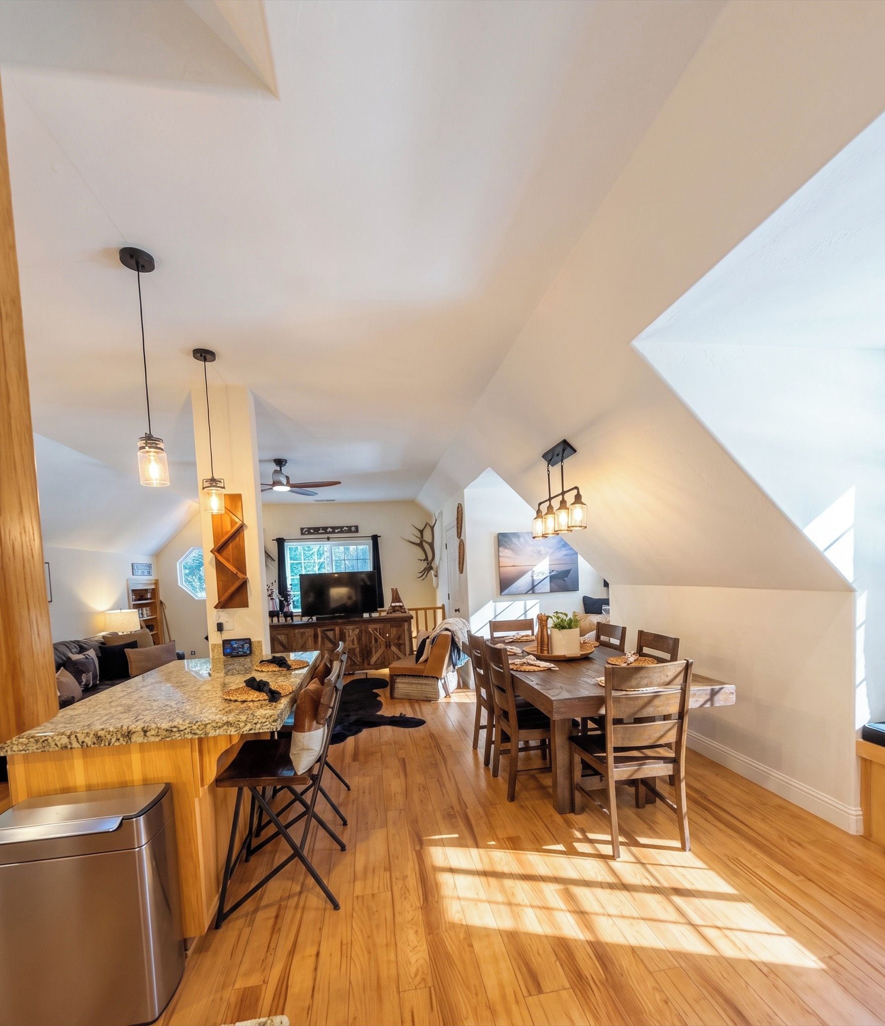 A spacious loft-style kitchen with a large dining area, wooden floors, and a ceiling fan.