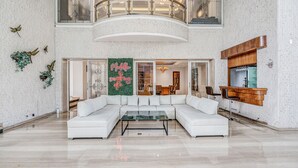 Amplia sala de estar con un sofá modular blanco, una mesa de centro de cristal y una pared decorativa con arte de mariposas.