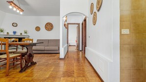 A hallway with a dining area, a sofa, and a staircase leading to another level.