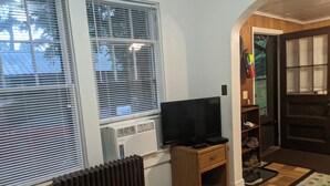 A room with a large window, a radiator, a wooden cabinet, and a door with glass panels. - Moreno's Cottages Cabin #10 -2 Bed/2 Bath Adirondack 4 season Cabin in the pines (Saranac Lake)