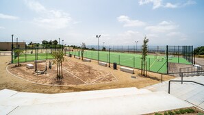 Una cancha deportiva con valla perimetral, bancos y árboles.