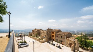 Un patio con edificios de piedra, un coche y vistas al campo.