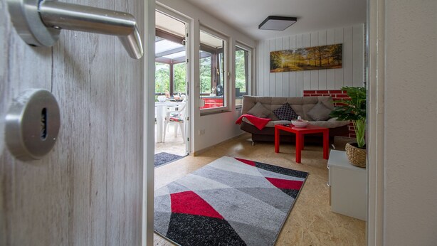 Uma sala de estar moderna com um sofá, uma mesa vermelha e uma janela grande.
