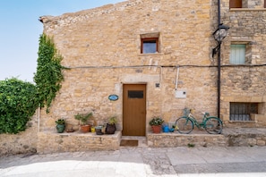 A stone building with a wooden door, potted plants, and a bicycle.