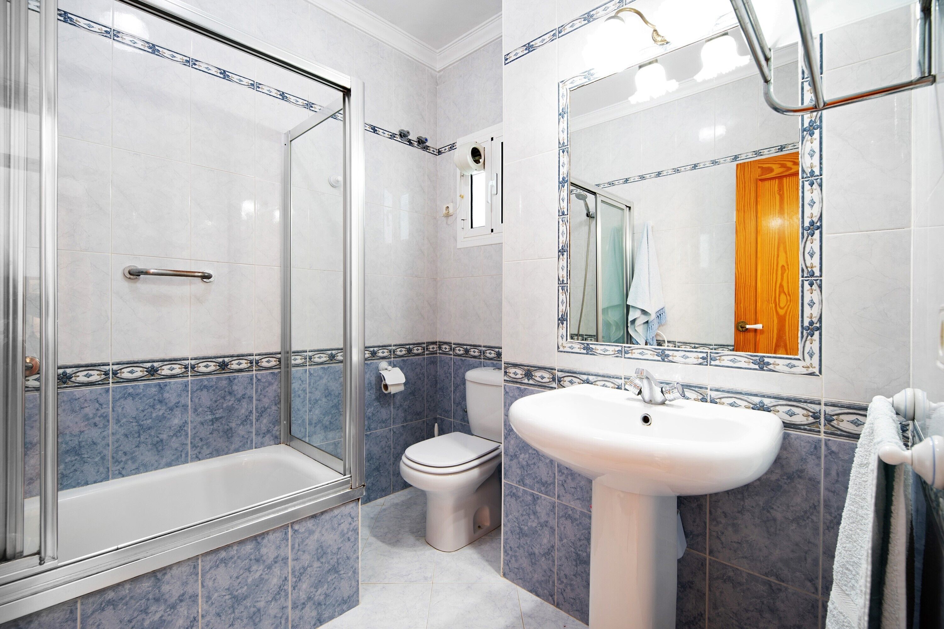 Un baño con ducha de vidrio, un lavamanos blanco y un inodoro.