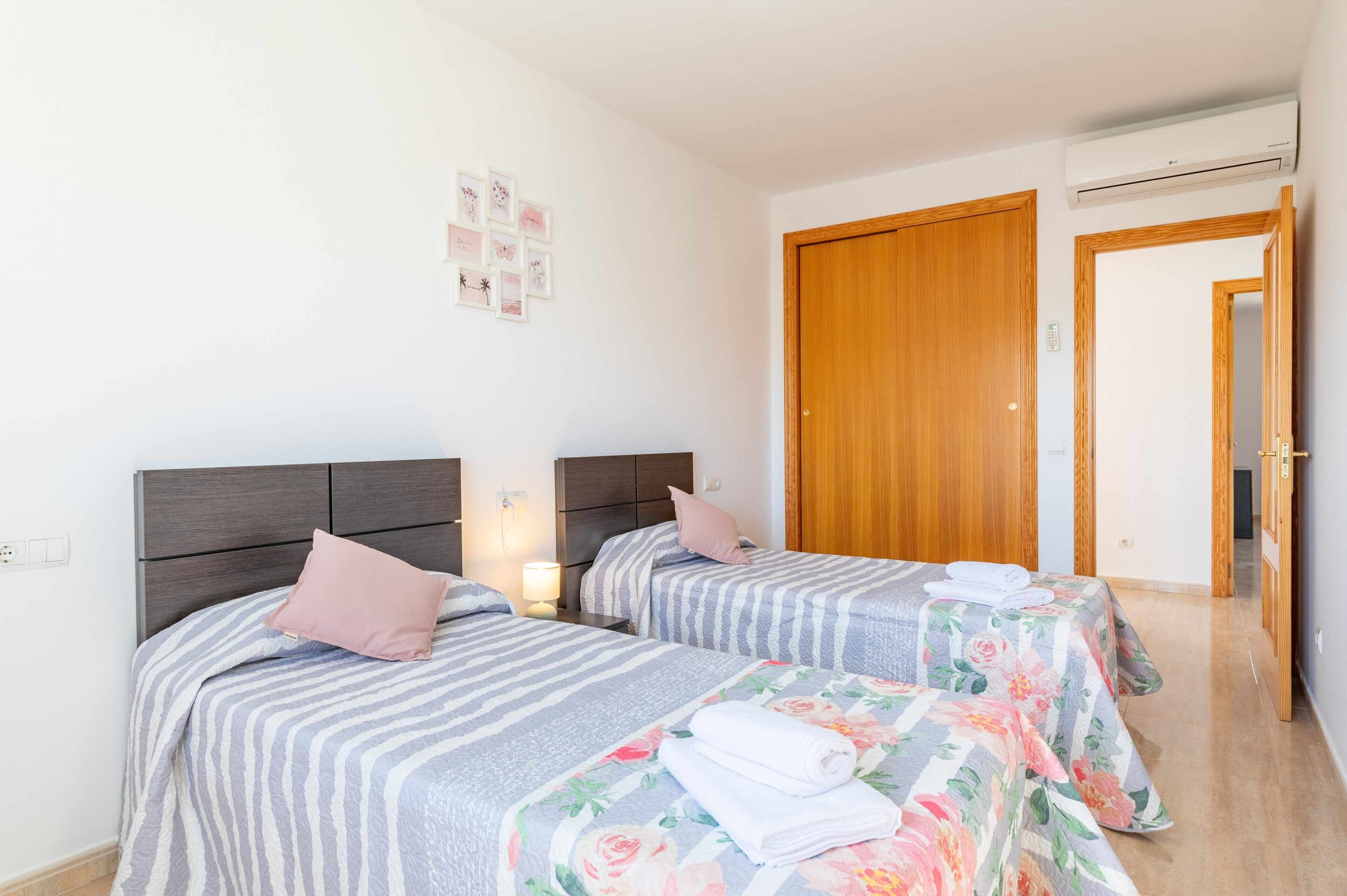 Habitación de hotel con dos camas, una puerta de madera y un pasillo.