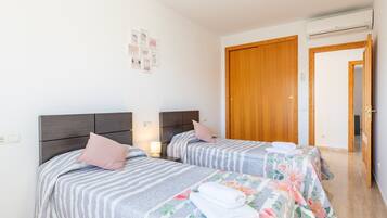 Habitación de hotel con dos camas, una puerta de madera y un pasillo.