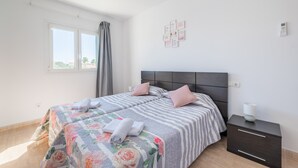 A bedroom with two beds, a nightstand, a window with curtains, and a wall-mounted alarm clock. - Apartment "Ferrera Soul 2B" near the beach with Wi-Fi and terrace (tourist taxes included) (Santanyí)