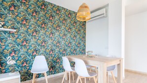 A dining area with a wooden table and white chairs, a decorative wall with a floral pattern, and a hanging light fixture. - Apartment "Ferrera Soul 2B" near the beach with Wi-Fi and terrace (tourist taxes included) (Santanyí)