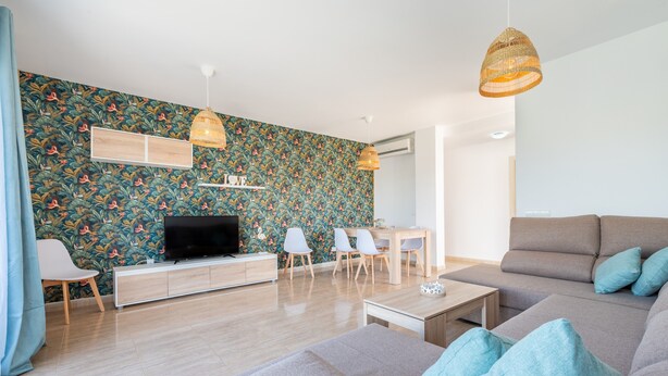 A modern living room with a flat-screen TV, grey sofa, and a dining area with chairs and a table. - Apartment "Ferrera Soul 2B" near the beach with Wi-Fi and terrace (tourist taxes included) (Santanyí)