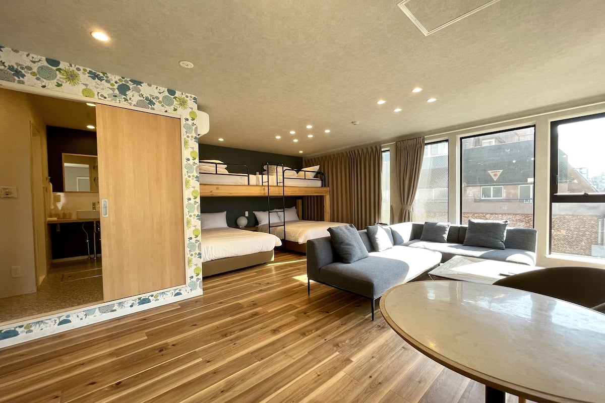 A modern, well-lit room with a bunk bed, a sofa, and a dining table.