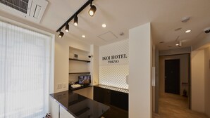 A modern hotel interior with a black countertop, a fire extinguisher, and a visible hallway leading to a door. - Ikoi Hotel Tokyo (Tokyo)