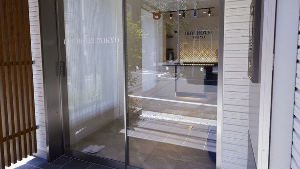 The entrance of the IKO Hotel Tokyo with a modern design, including a glass door and a wooden fence. - Ikoi Hotel Tokyo (Tokyo)