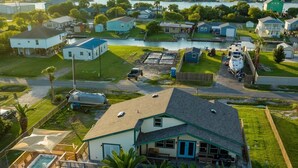 Un quartier résidentiel où se trouve une maison dotée d’une grande terrasse, d’un jacuzzi et d’un quai s’avançant dans un plan d’eau.