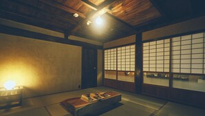 Een traditionele Japanse kamer met tatami vloerbedekking, een lage houten tafel, schuivende shoji deuren en een plafondlamp.