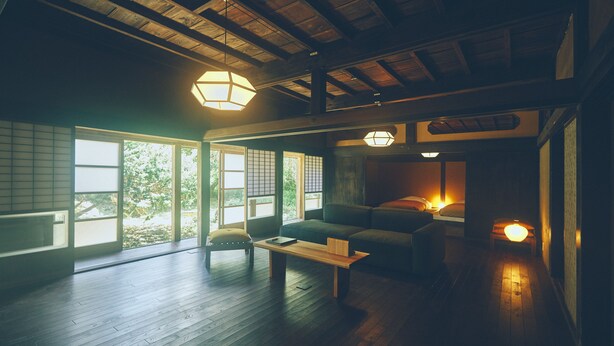 Een traditionele Japanse kamer met tatami vloerbedekking, een lage houten tafel en een bank.
