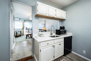 A compact kitchen with white cabinets, a microwave, and a dishwasher.