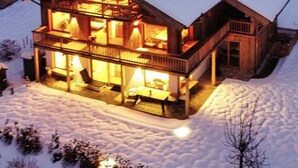 A two-story wooden house with a balcony, surrounded by snow. - Gipfelhütte - mit Masterschlafzimmer, Zwei Hüttenzimmer und Balkon (Reit im Winkl)