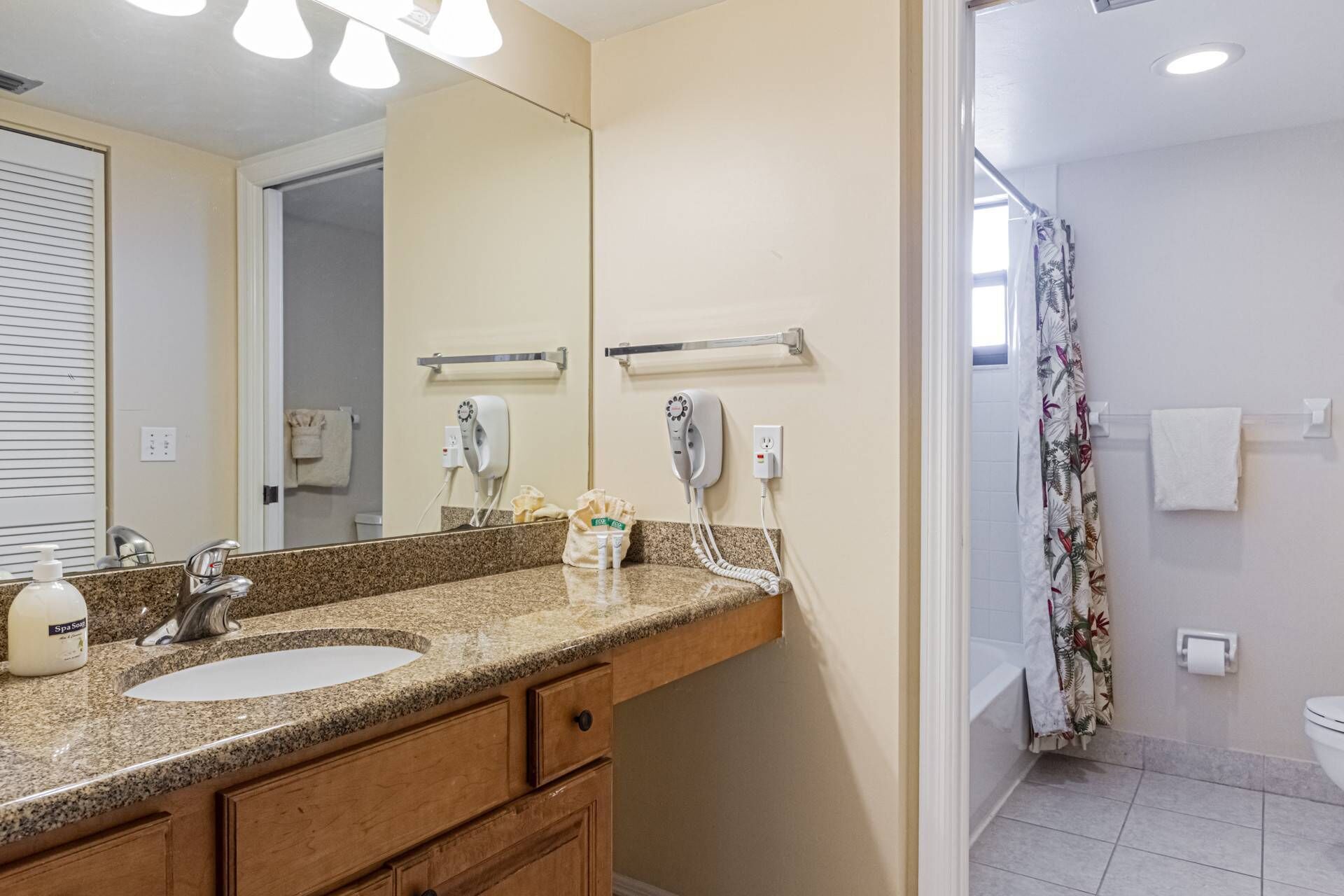 A bathroom with two sinks, a mirror, a hairdryer, and a shower curtain.