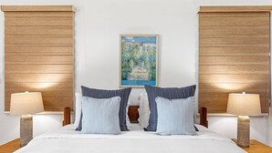 Quarto de hotel com uma cama grande, duas mesas de cabeceira com abajures e um quadro emoldurado na parede.