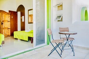 Une pièce comprenant un lit, une chaise, une table, une armoire en bois et une porte portant un numéro.