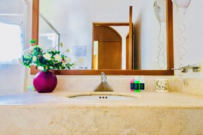 A bathroom with a sink, mirror, and a vase of flowers.