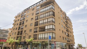 Un immeuble à plusieurs étages doté de balcons, de grandes fenêtres et d’un magasin situé au rez-de-chaussée.