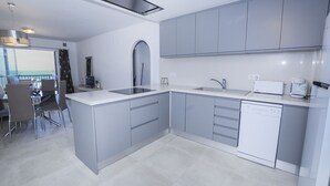 Une cuisine moderne avec des meubles gris, un lave-vaisselle et un coin repas comprenant une table et des chaises.