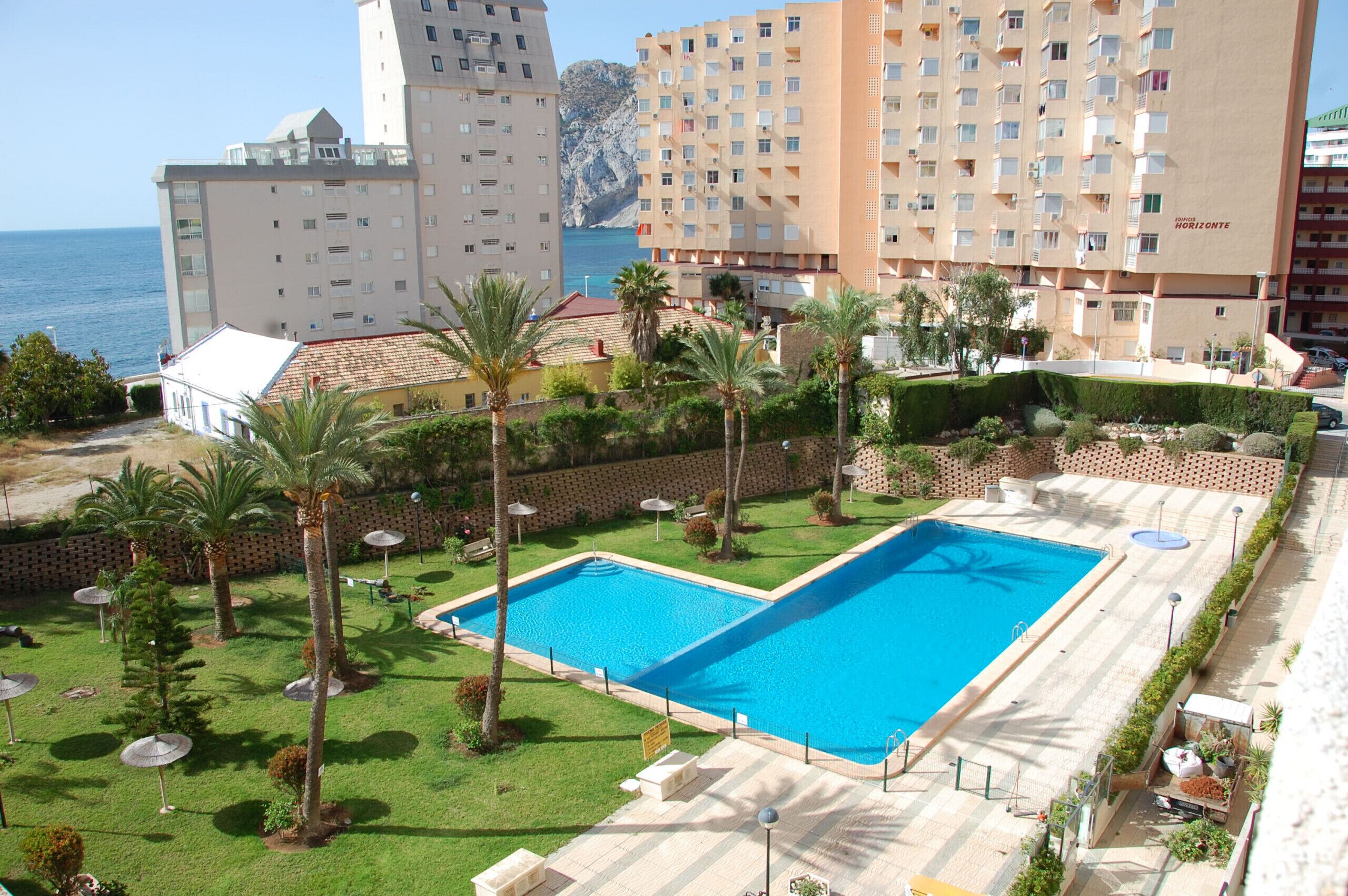 Un hôtel doté d’une piscine, de palmiers et offrant une vue sur la mer.