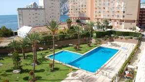 A hotel with a swimming pool, palm trees, and a view of the sea. - A75 CALPPLACE ESC 1 5º 3 (Calpe)