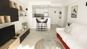 Una sala moderna con un televisor de pantalla plana, una mesa de centro de vidrio y un sofá rojo.