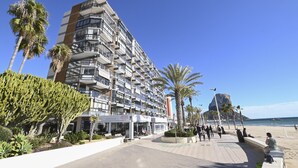 Un hotel de varios pisos con balcones, un restaurante y vistas a la playa y al océano.