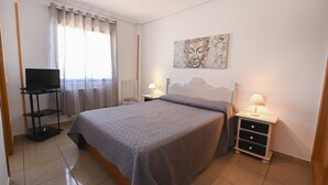 Una camera da letto con un letto, una televisione, un comodino, una lampada e un quadro appeso al muro.