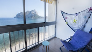 Un balcon avec vue sur la mer et les montagnes, un hamac et une chaise bleue.