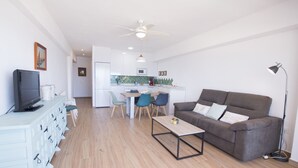 A modern living room with a sofa, coffee table, TV, and a dining area with chairs and a table. - A38 CALPEMAR B 2º - 5 (Calpe / Calp)
