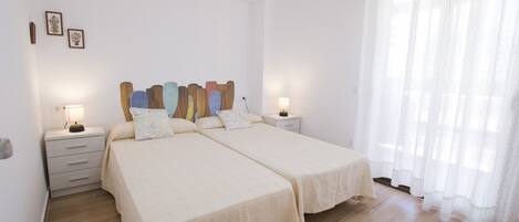 A double bed with a matching nightstand, a bedside table, and a wall-mounted lamp.