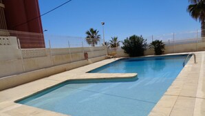 A rectangular swimming pool with a tiled deck, surrounded by a white fence and palm trees. - A38 CALPEMAR B 2º - 5 (Calpe / Calp)