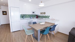 A modern kitchen with white cabinets, a wooden dining table, and blue chairs. - A38 CALPEMAR B 2º - 5 (Calpe / Calp)
