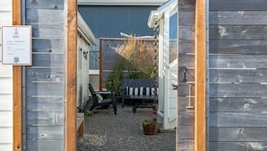 A wooden deck with a bench and potted plants, a sign indicating short-term rental availability, and a fence with climbing plants. - 2 Bedroom Vintage Beach Bungalow steps to downtown Rockaway and Rockaway Beach (Rockaway Beach)