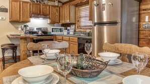 Una cucina con mobili in legno, un frigorifero in acciaio inossidabile e un'area pranzo con tavolo imbandito per quattro.