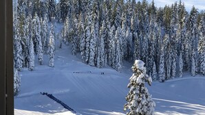 Un paisaje nevado con una terraza de madera y árboles cubiertos de nieve.