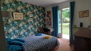 A bedroom with a bed, a bookshelf, a desk, and a view of the outdoors.