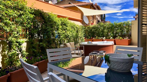 A patio with a table and chairs, surrounded by potted plants and a view of neighboring buildings. - Casa Mando Terrace With Private Jacuzzi - Taormina (Taormina)