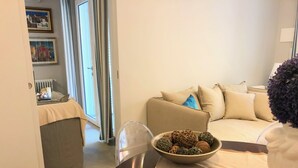 A living room with a sofa, a table with a bowl of decorative items, and a door leading to another room. - Casa Mando Terrace With Private Jacuzzi - Taormina (Taormina)