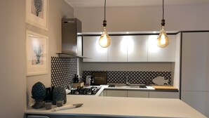 A modern kitchen with a central island, pendant lighting, and a patterned backsplash. - Casa Mando Terrace With Private Jacuzzi - Taormina (Taormina)