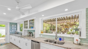 A modern kitchen with white cabinetry, a double sink, and a dishwasher.
