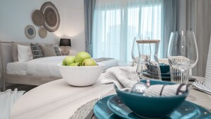 A neatly arranged dining table with a bowl of green apples, a blue bowl, and clear glassware. - HiGuests - Elite Business Bay (Dubai)